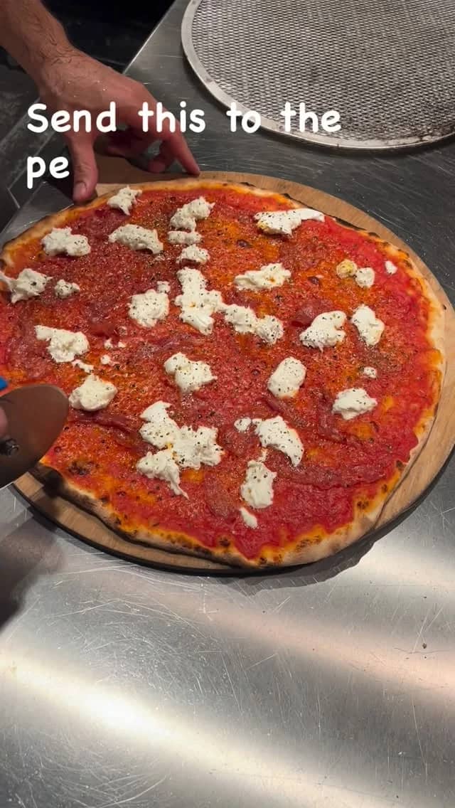 Pizza rossa mit Salami piccante und Mozzarella di bufala wird geschnitten
